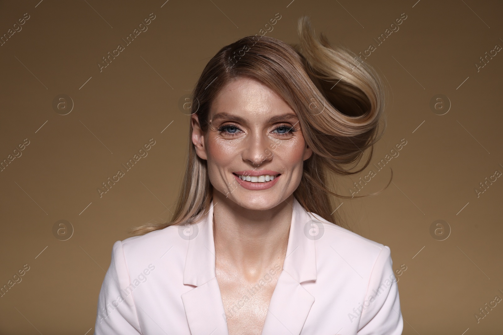 Photo of Portrait of beautiful happy woman with straight blonde hair on light brown background