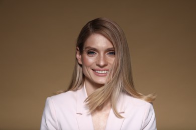 Photo of Portrait of beautiful happy woman with straight blonde hair on light brown background