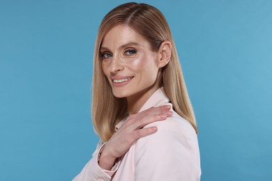 Photo of Portrait of beautiful happy woman with straight blonde hair on light blue background