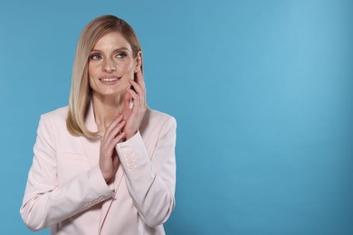 Photo of Beautiful happy woman with straight blonde hair on light blue background, space for text