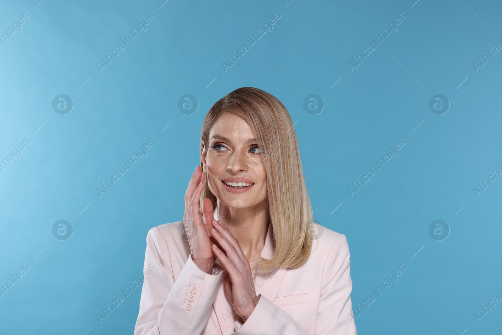 Photo of Portrait of beautiful happy woman with straight blonde hair on light blue background