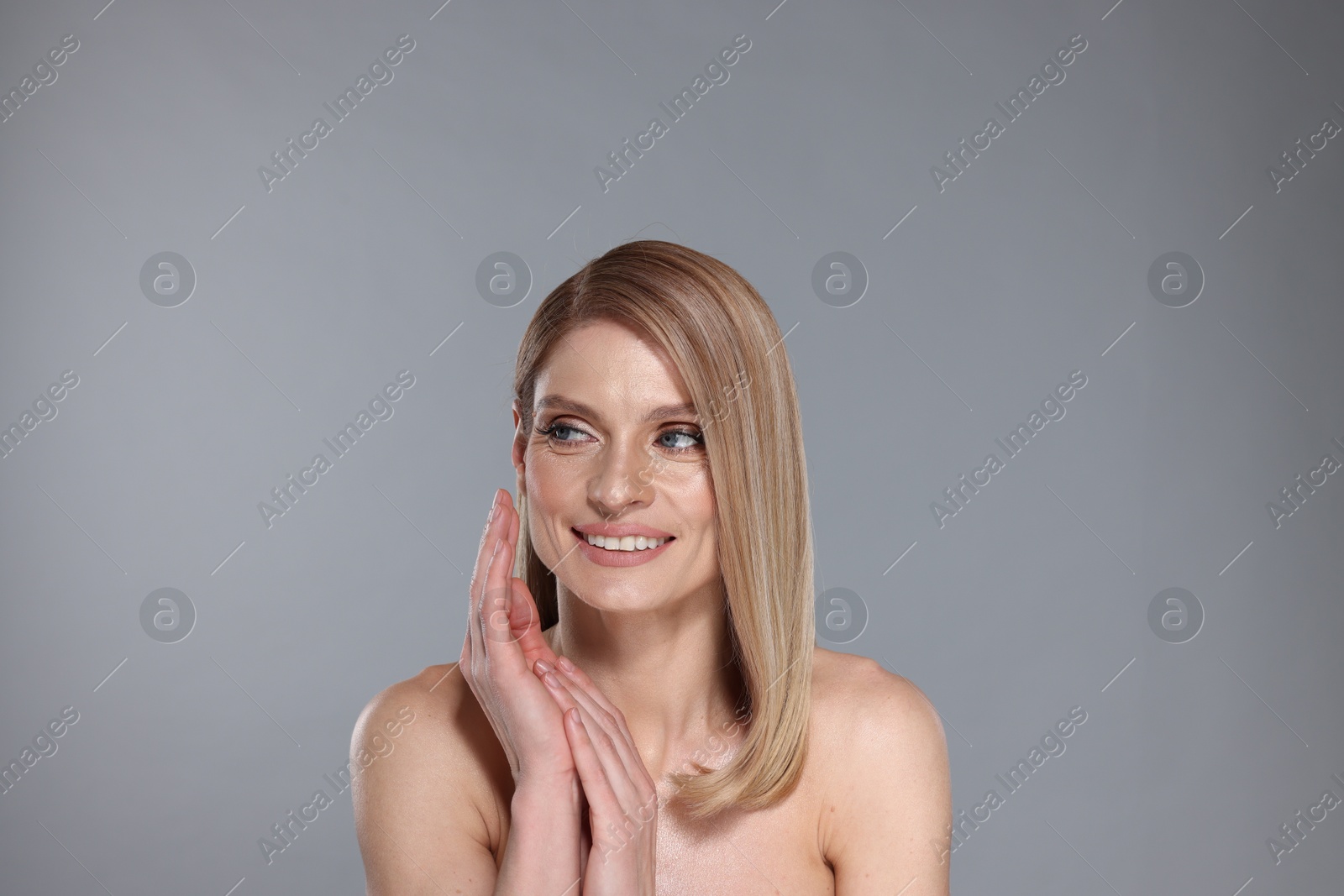 Photo of Portrait of beautiful happy woman with straight blonde hair on grey background