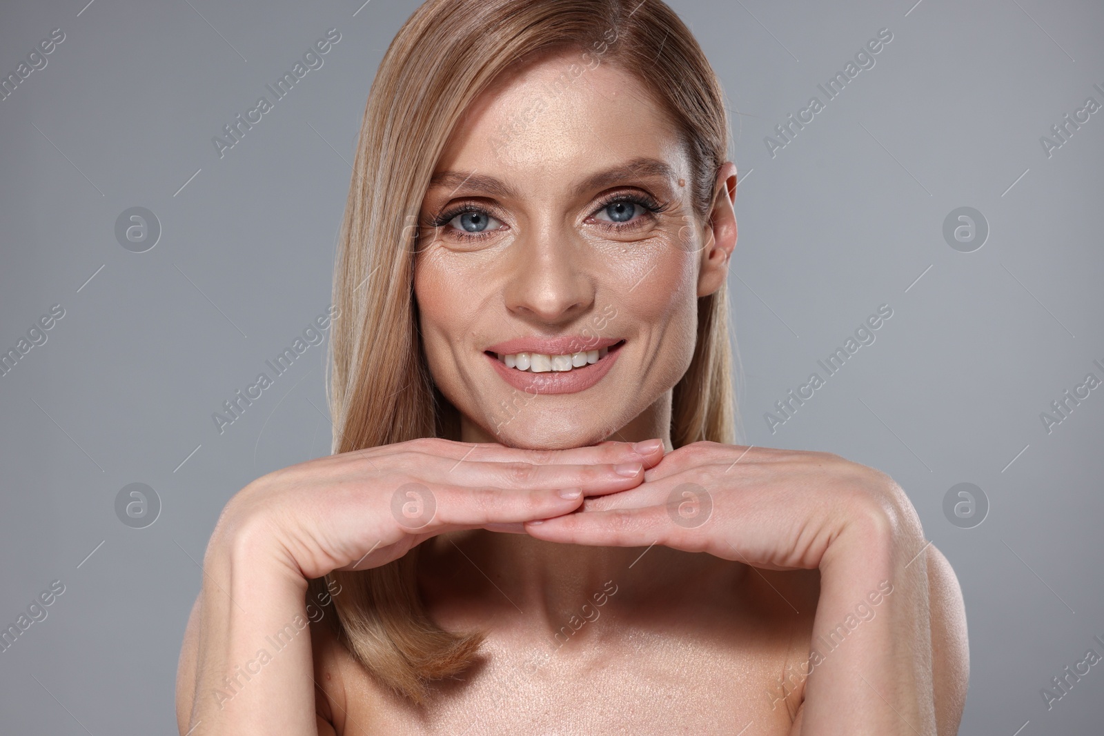 Photo of Portrait of beautiful happy woman with straight blonde hair on grey background