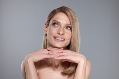 Photo of Portrait of beautiful happy woman with straight blonde hair on grey background