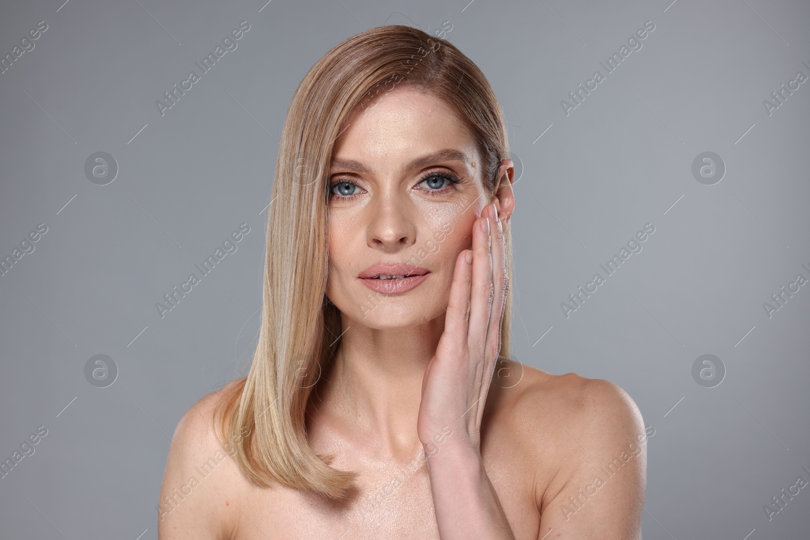 Photo of Portrait of beautiful woman with straight blonde hair on grey background