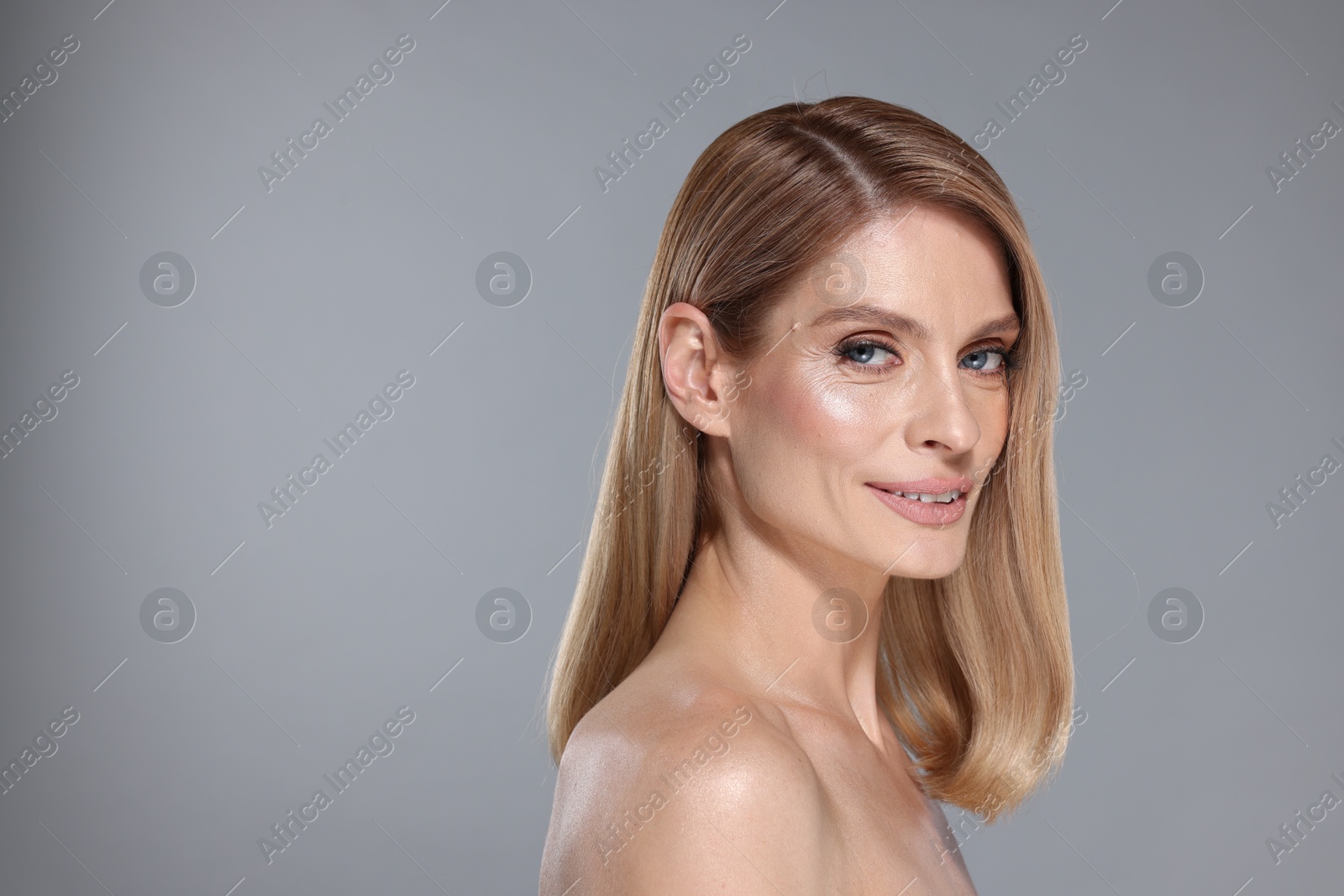 Photo of Portrait of beautiful happy woman with straight blonde hair on grey background, space for text