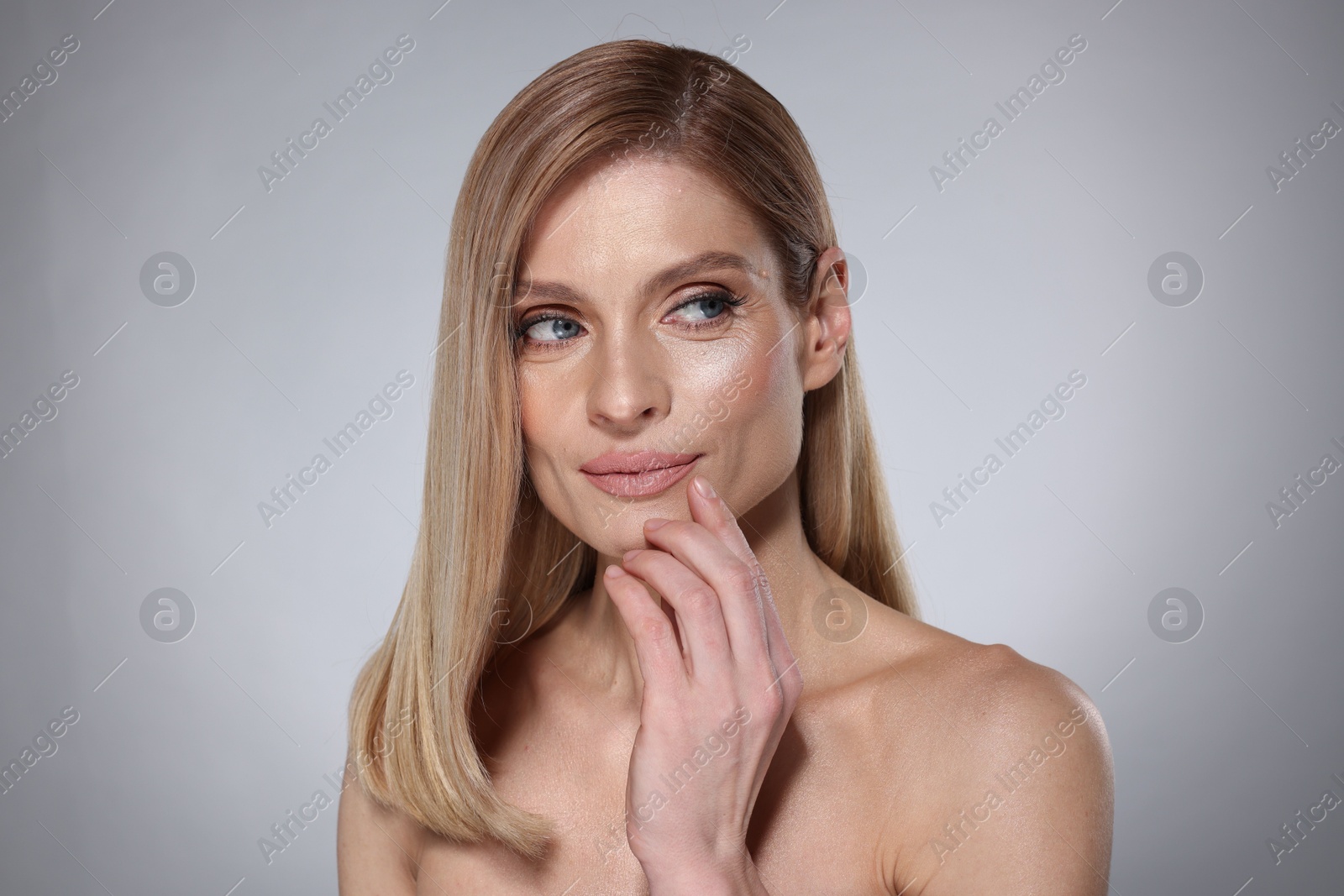 Photo of Portrait of beautiful woman with straight blonde hair on grey background