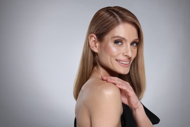 Photo of Portrait of beautiful happy woman with straight blonde hair on grey background