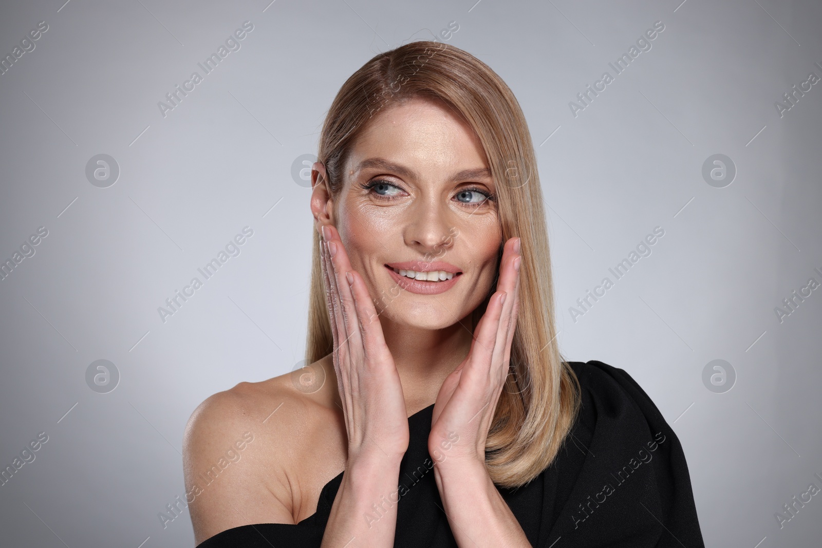 Photo of Portrait of beautiful happy woman with straight blonde hair on grey background