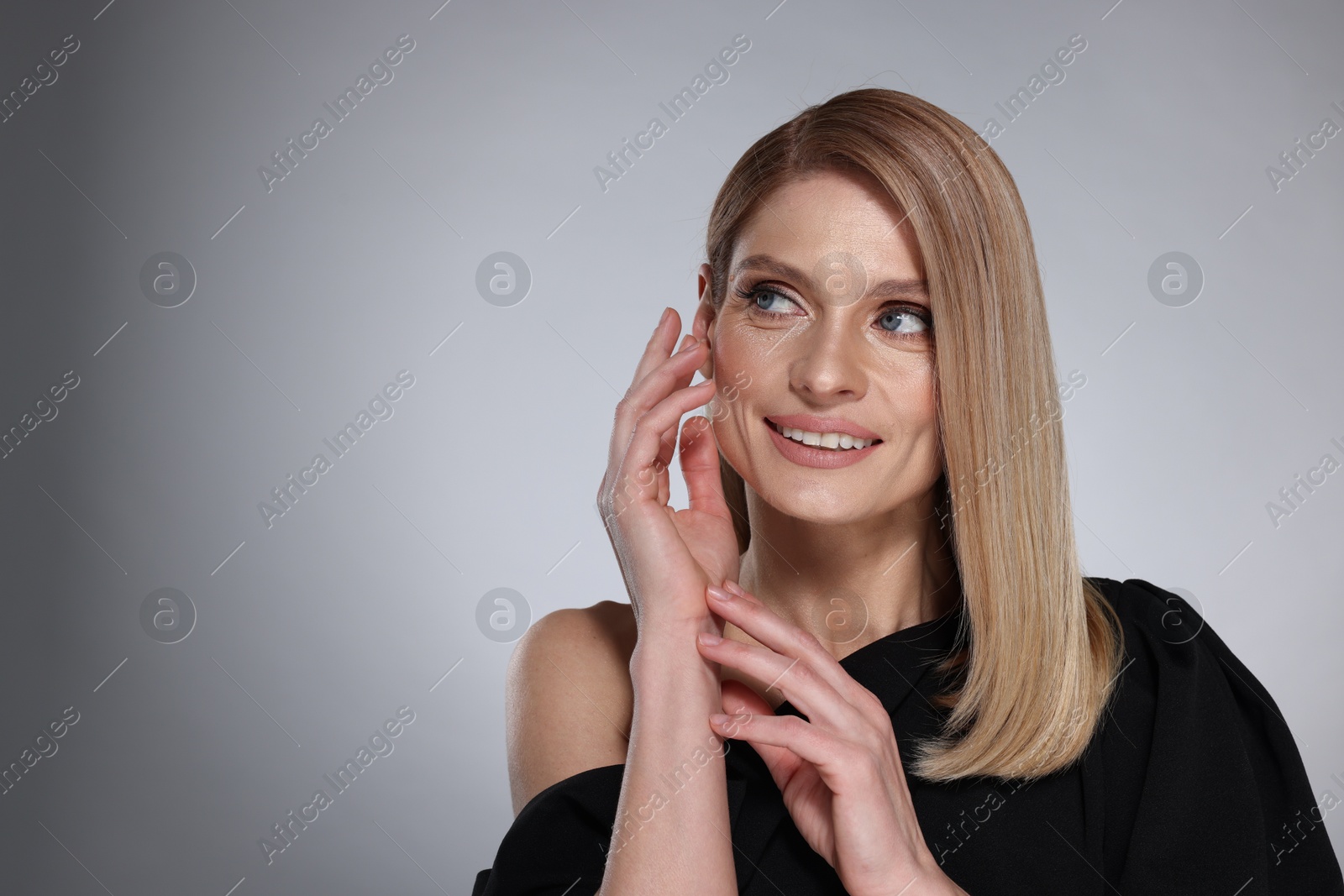 Photo of Portrait of beautiful happy woman with straight blonde hair on grey background, space for text