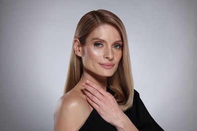 Photo of Portrait of beautiful woman with straight blonde hair on grey background