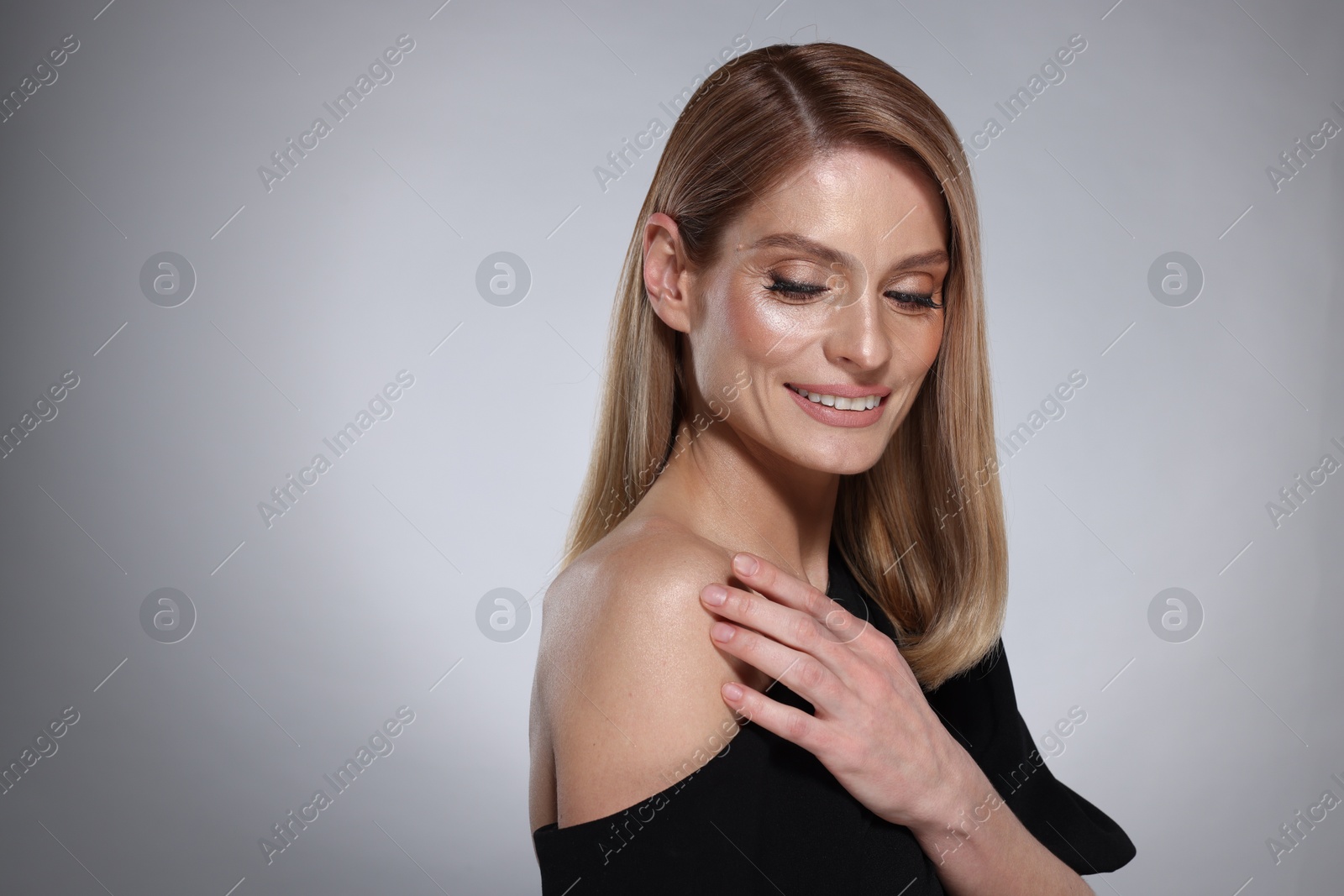 Photo of Portrait of beautiful happy woman with straight blonde hair and stylish makeup on grey background. Space for text