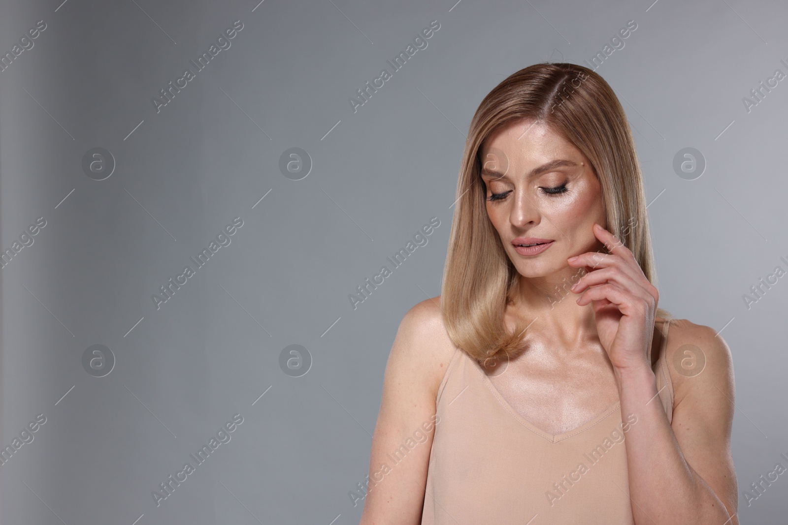 Photo of Portrait of beautiful woman with straight blonde hair and stylish makeup on light grey background, space for text