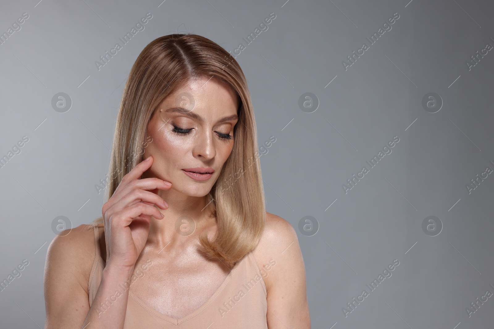 Photo of Portrait of beautiful woman with straight blonde hair and stylish makeup on light grey background, space for text