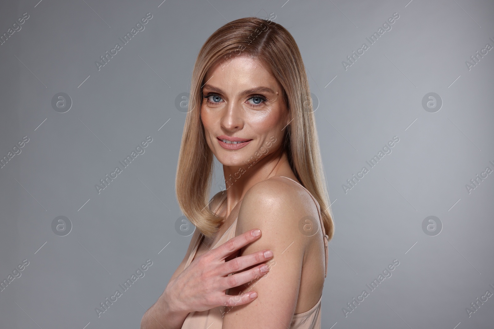 Photo of Portrait of beautiful woman with straight blonde hair on grey background