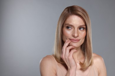 Photo of Portrait of beautiful woman with straight blonde hair on grey background, space for text