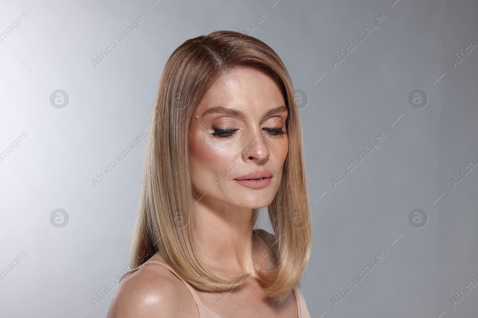 Photo of Portrait of beautiful woman with straight blonde hair and stylish makeup on light grey background