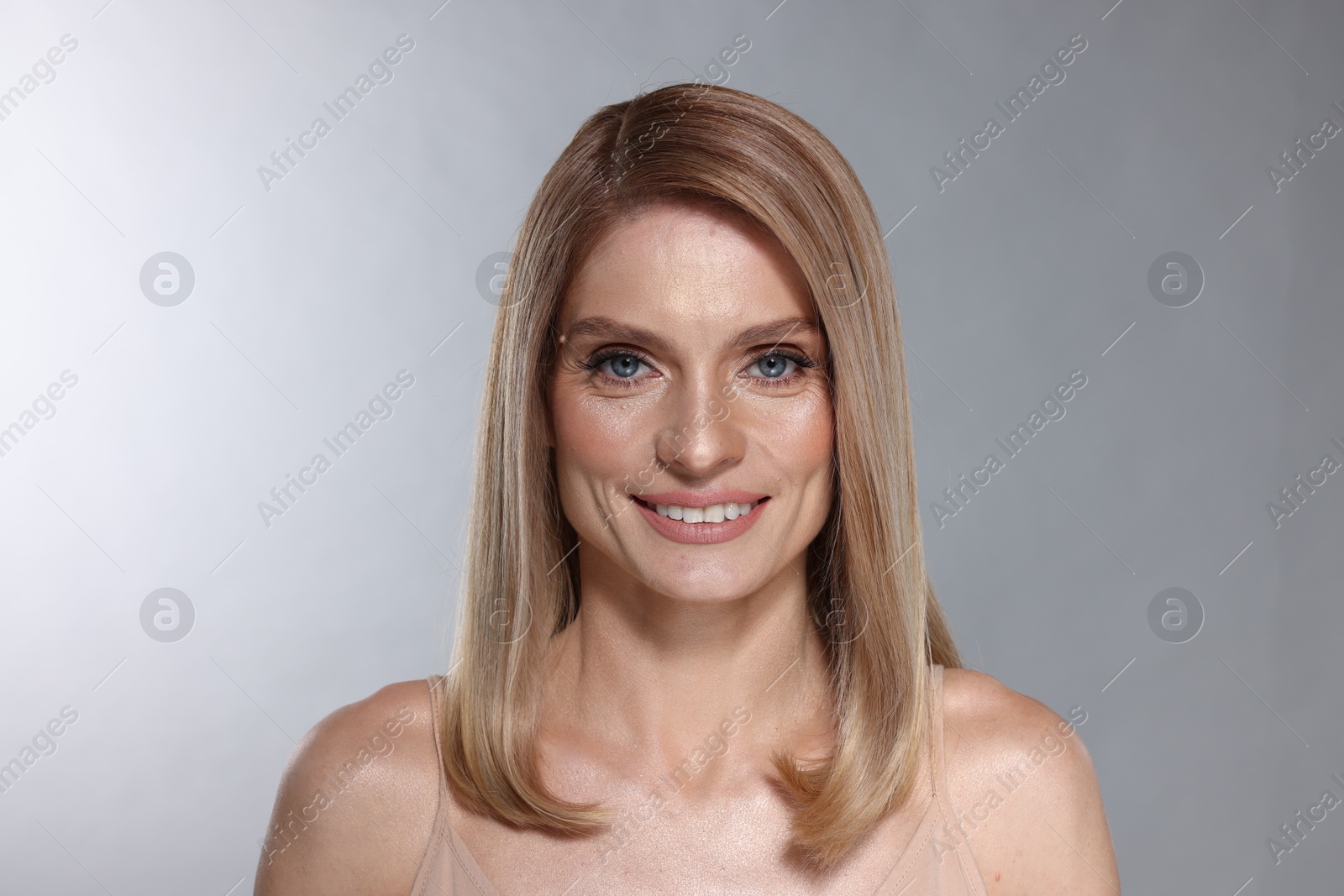 Photo of Portrait of beautiful happy woman with straight blonde hair on light grey background