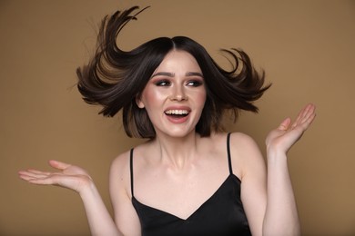 Photo of Portrait of beautiful young happy woman with gorgeous straight hair on dark beige background