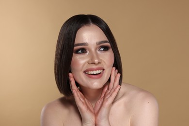 Photo of Portrait of beautiful young happy woman with gorgeous straight hair on beige background