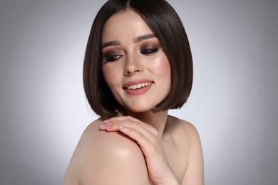 Photo of Portrait of beautiful young happy woman with gorgeous straight hair on light grey background