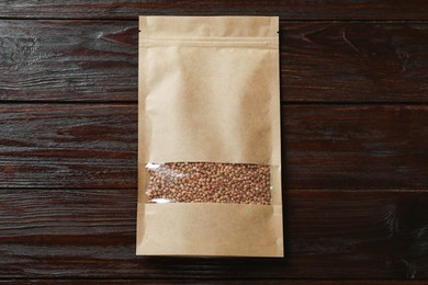 Photo of Paper pouch bag with buckwheat on wooden table, top view