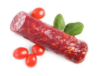 Photo of Piece of delicious dry cured sausage with basil and tomatoes isolated on white, top view