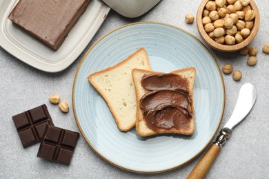 Photo of Sandwiches with chocolate butter, hazelnuts and knife on grey table, flat lay