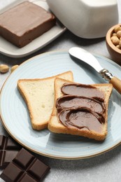 Photo of Sandwiches with chocolate butter, hazelnuts and knife on grey table, closeup