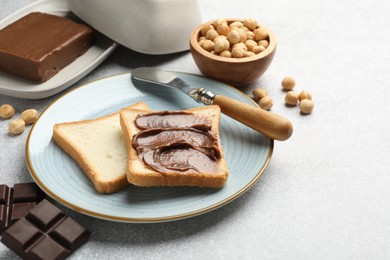 Sandwiches with chocolate butter, hazelnuts and knife on grey table, closeup. Space for text