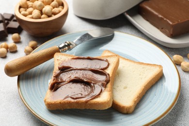 Photo of Sandwiches with chocolate butter, hazelnuts and knife on grey table, closeup