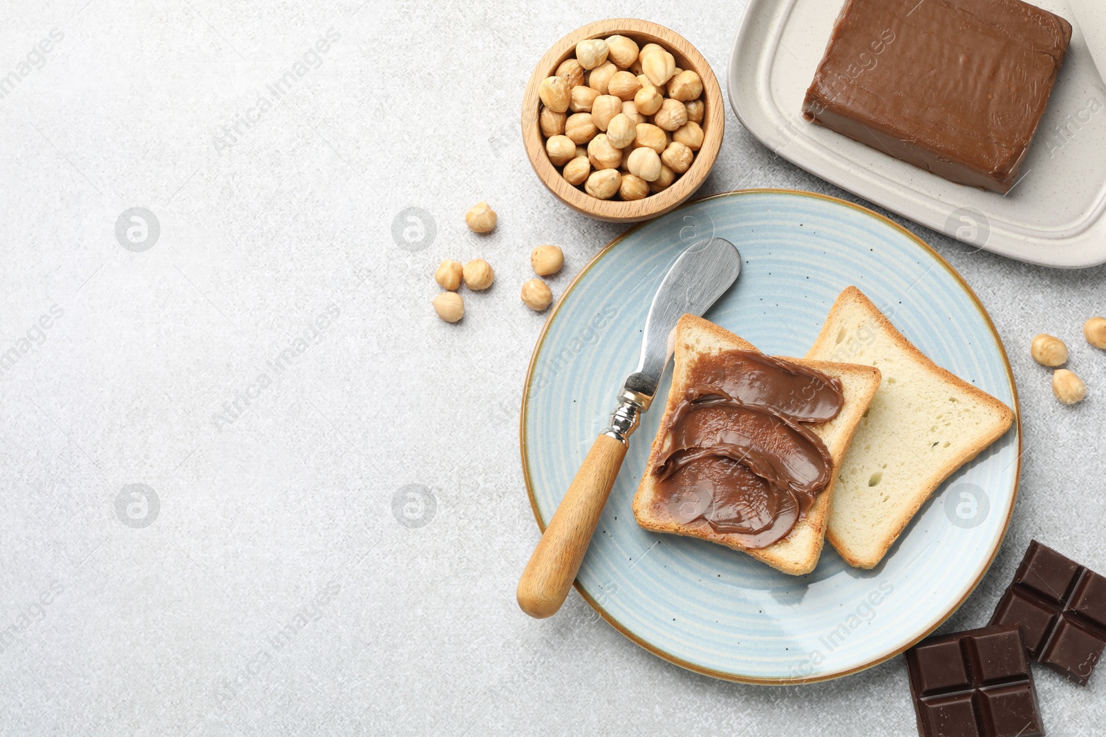 Photo of Sandwiches with chocolate butter, hazelnuts and knife on grey table, flat lay. Space for text