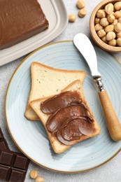 Photo of Sandwiches with chocolate butter, hazelnuts and knife on grey table, flat lay