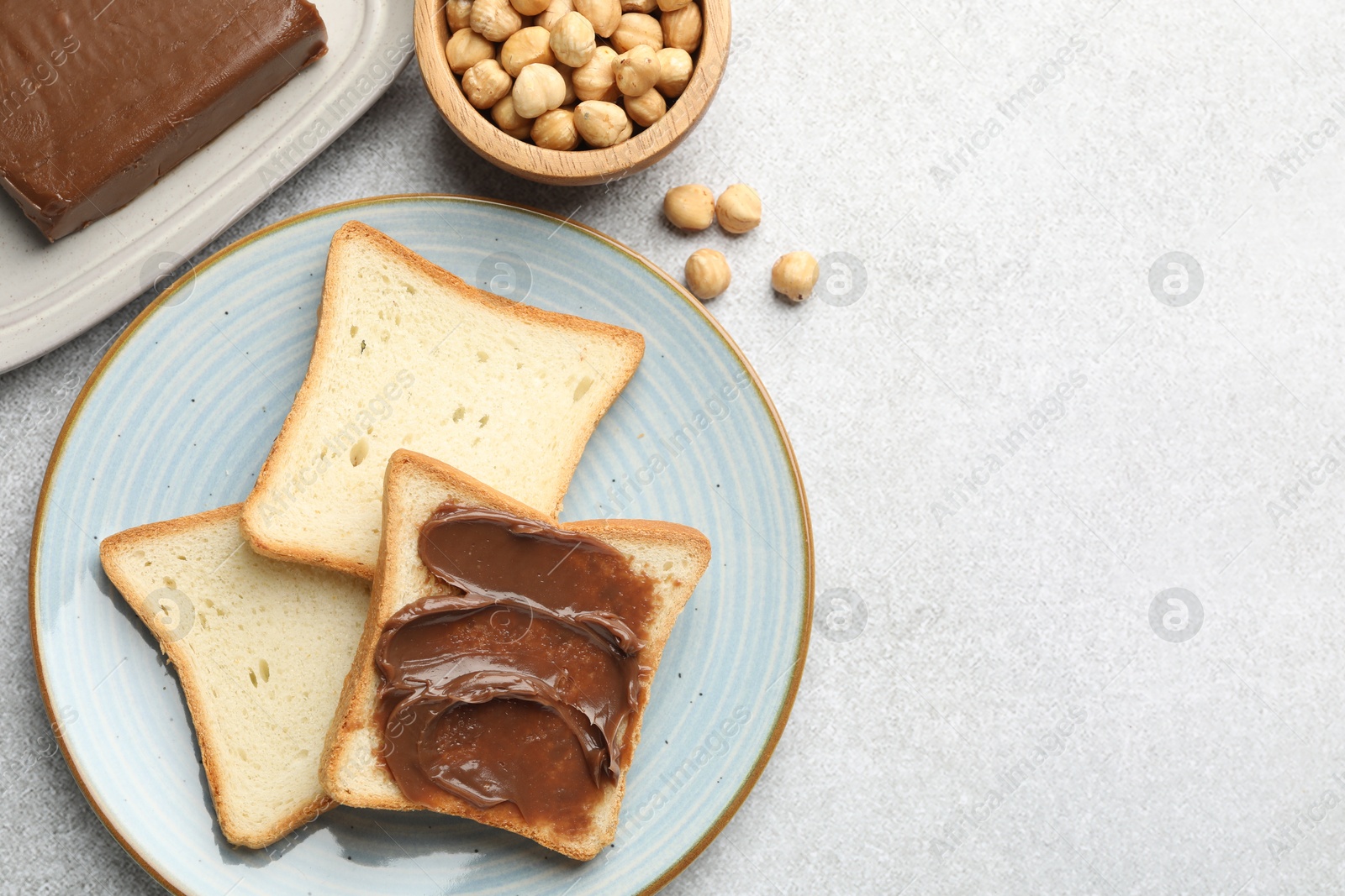 Photo of Sandwiches with chocolate butter and hazelnuts on grey table, flat lay. Space for text