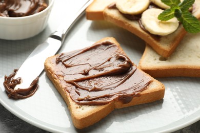 Sandwiches with chocolate butter, banana, mint and knife on table, closeup