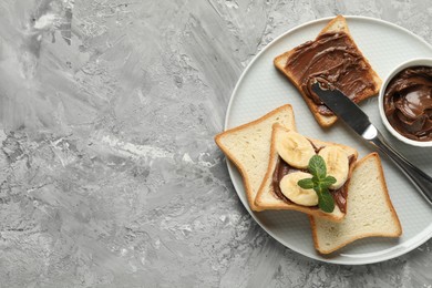 Sandwiches with chocolate butter, banana, mint and knife on grey table, top view. Space for text