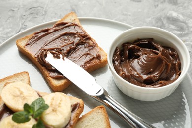 Photo of Sandwiches with chocolate butter, banana, mint and knife on grey table, closeup