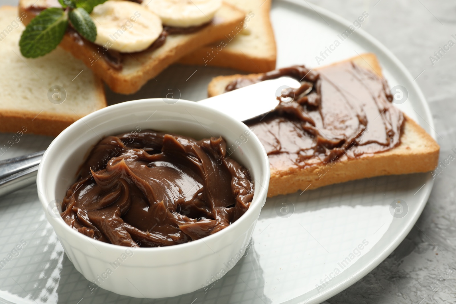 Photo of Sandwiches with chocolate butter, banana, mint and knife on grey table, closeup