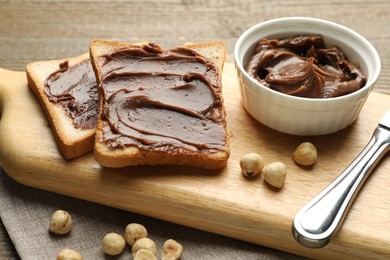 Photo of Sandwiches with chocolate butter, hazelnuts and knife on table, closeup