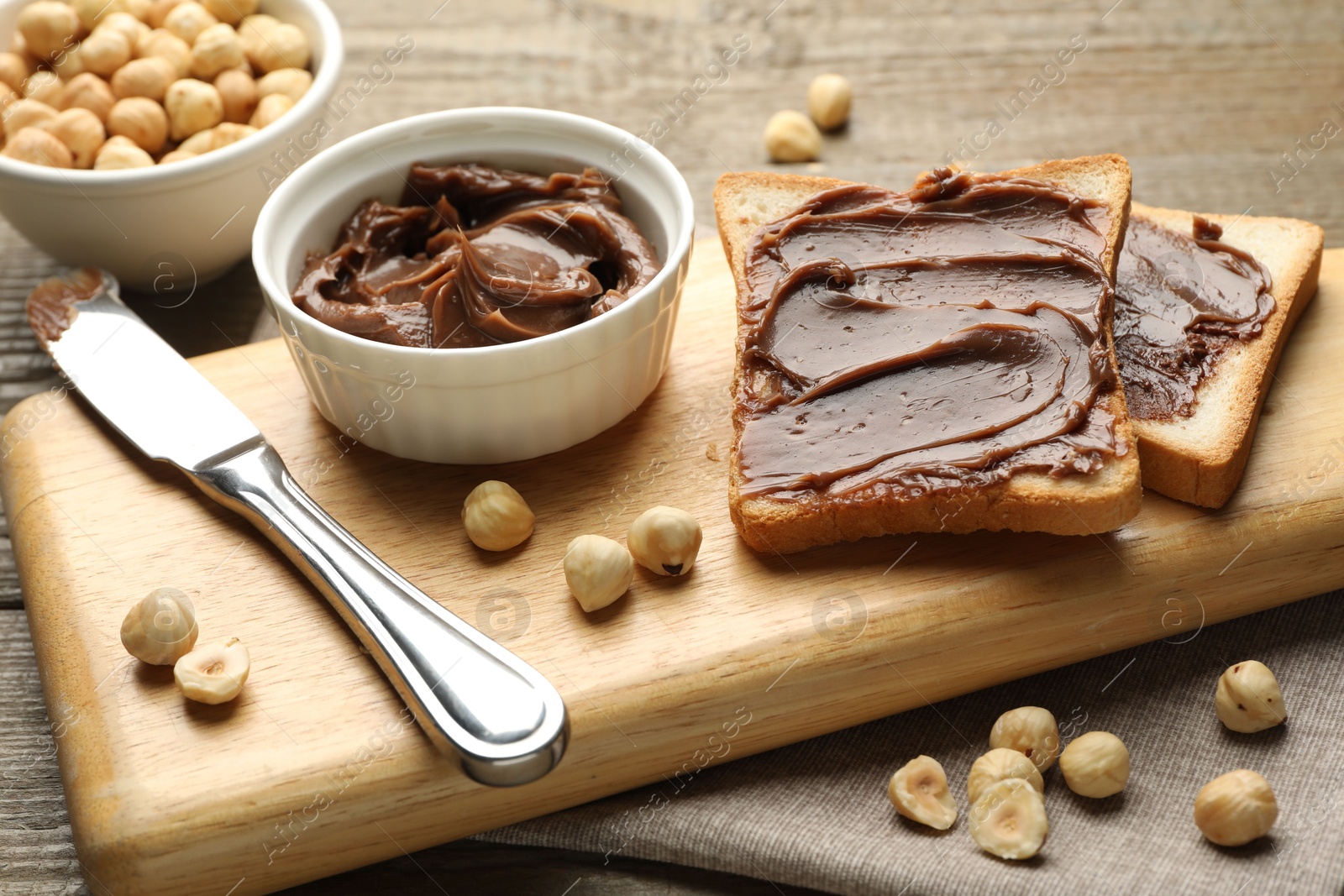 Photo of Sandwiches with chocolate butter, hazelnuts and knife on table, closeup