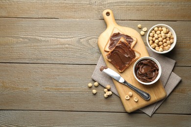 Photo of Sandwiches with chocolate butter, hazelnuts and knife on wooden table, flat lay. Space for text