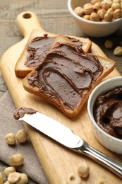 Photo of Sandwiches with chocolate butter, hazelnuts and knife on table, closeup