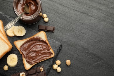 Photo of Sandwich with chocolate butter, banana and hazelnuts on black table, flat lay. Space for text