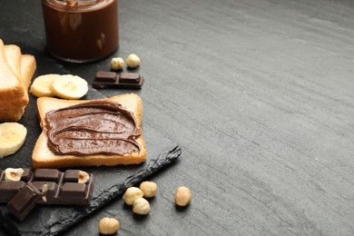 Sandwich with chocolate butter, banana and hazelnuts on black table, closeup. Space for text