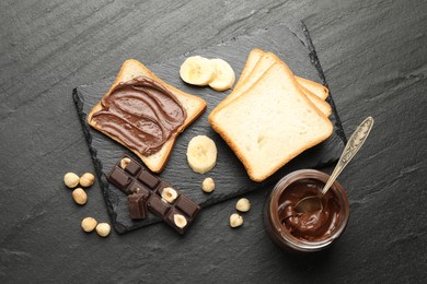 Photo of Sandwich with chocolate butter, banana and hazelnuts on black table, flat lay