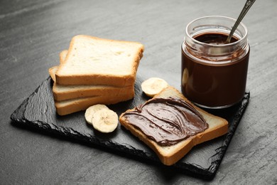 Photo of Sandwich with chocolate butter and banana on black table, closeup