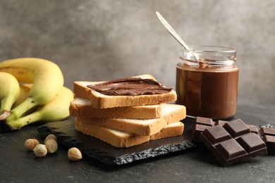 Photo of Sandwich with chocolate butter, hazelnuts and bananas on black table, closeup