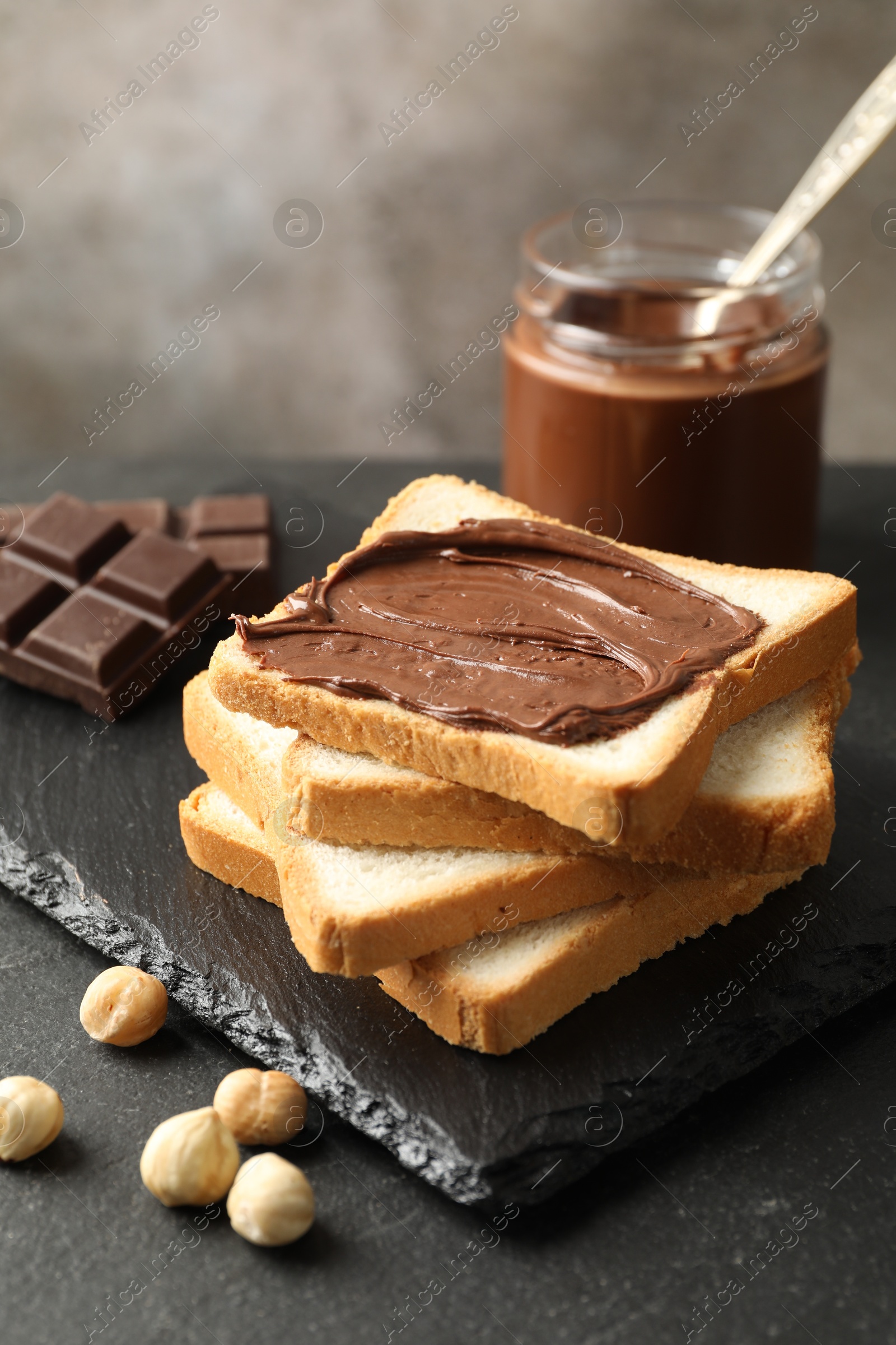 Photo of Sandwich with chocolate butter and hazelnuts on black table, closeup