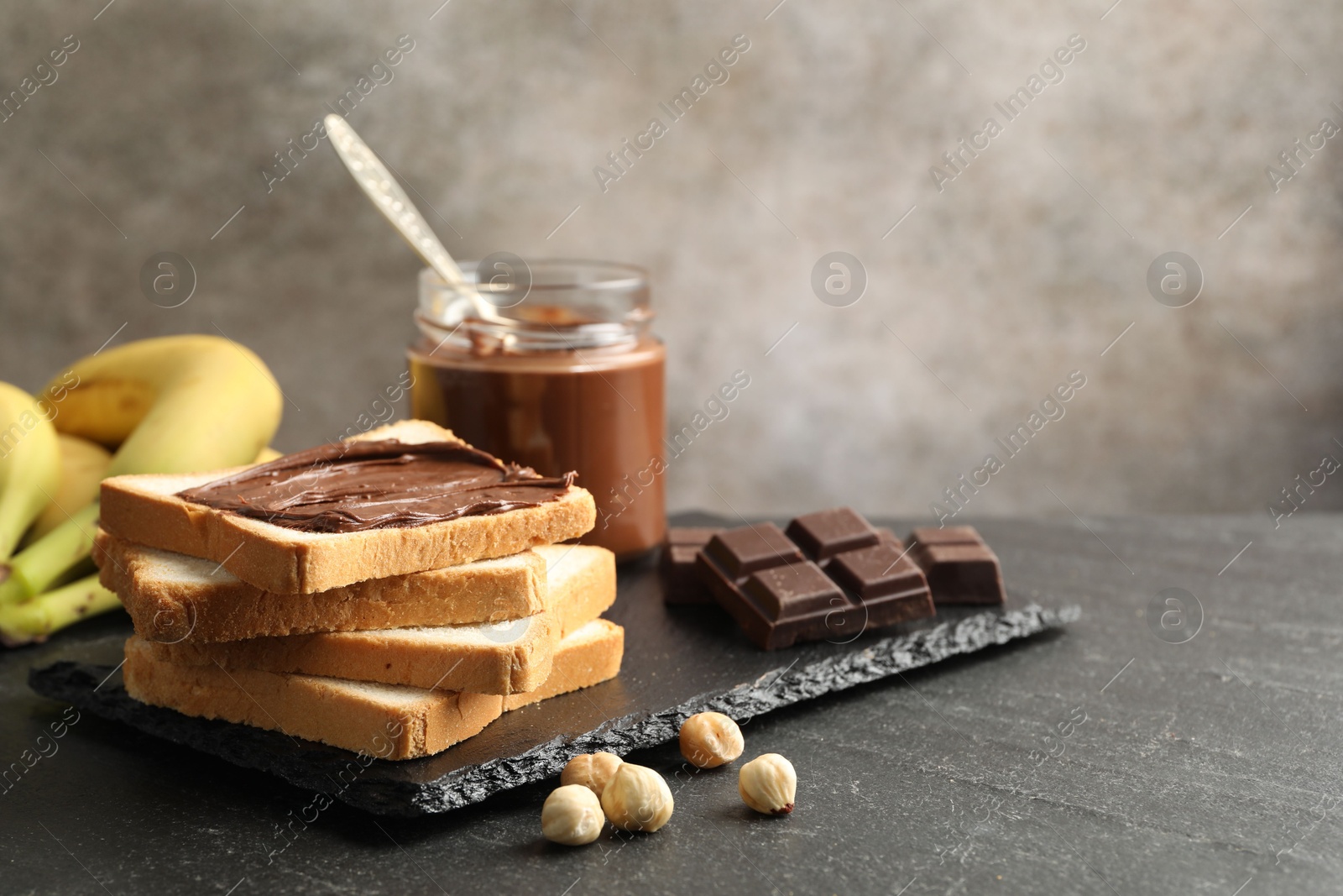 Photo of Sandwich with chocolate butter, hazelnuts and bananas on black table, closeup. Space for text