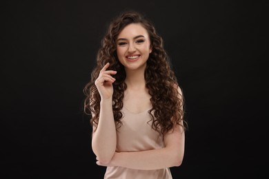 Photo of Beautiful young woman with long curly brown hair on black background